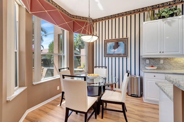 dining space with light wood-type flooring, healthy amount of natural light, baseboards, and wallpapered walls