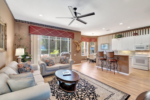 living area with ceiling fan, light wood-type flooring, recessed lighting, and baseboards