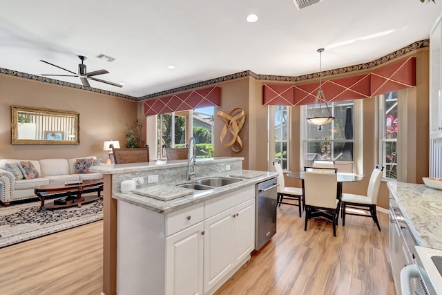 kitchen with a sink, open floor plan, light wood-style floors, ceiling fan, and white cabinets