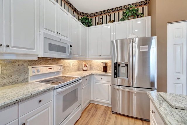 kitchen featuring white appliances, white cabinets, light wood-type flooring, and backsplash