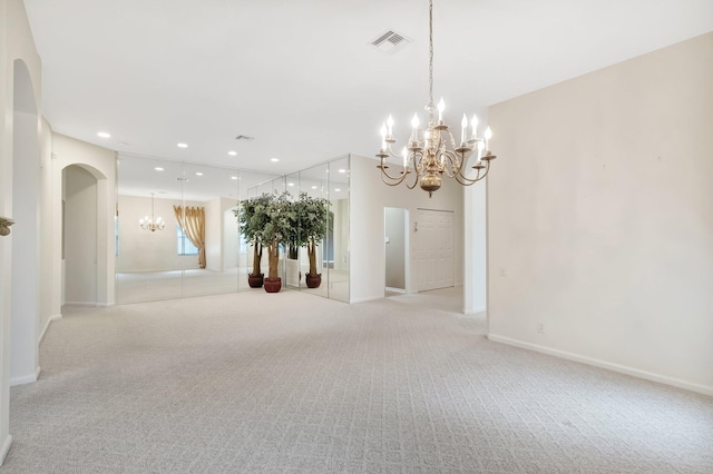 spare room with a chandelier, light colored carpet, recessed lighting, arched walkways, and baseboards