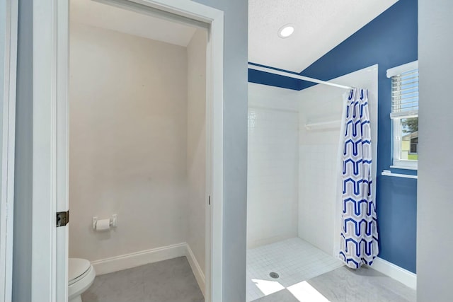 full bathroom with toilet, baseboards, tiled shower, and tile patterned floors