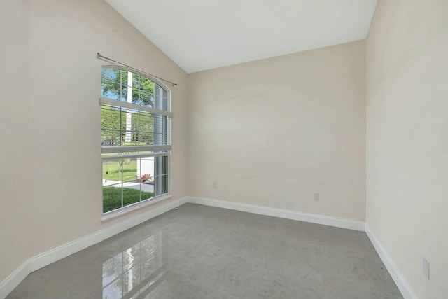 empty room featuring lofted ceiling and baseboards