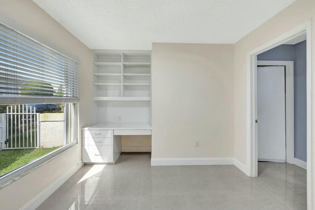 interior space featuring built in desk, baseboards, and a textured ceiling