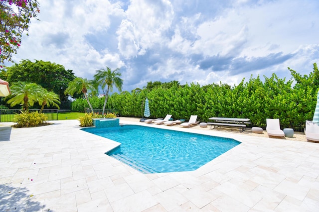 view of pool featuring a patio, a pool with connected hot tub, and fence