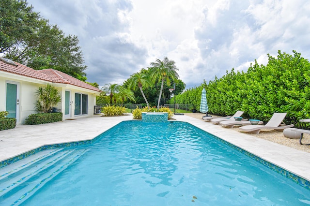 view of swimming pool featuring a patio area, a pool with connected hot tub, and fence