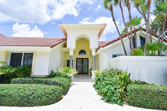 view of front facade featuring a tiled roof, french doors, and stucco siding