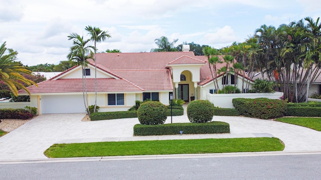 mediterranean / spanish home with driveway, a chimney, stucco siding, a garage, and a tiled roof