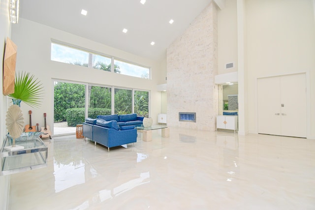 living room with visible vents, marble finish floor, recessed lighting, a high ceiling, and a stone fireplace