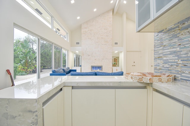 kitchen with white cabinets, a fireplace, open floor plan, and high vaulted ceiling