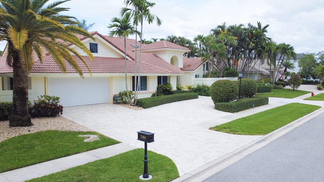 view of front of house featuring an attached garage, a tile roof, a front yard, stucco siding, and driveway