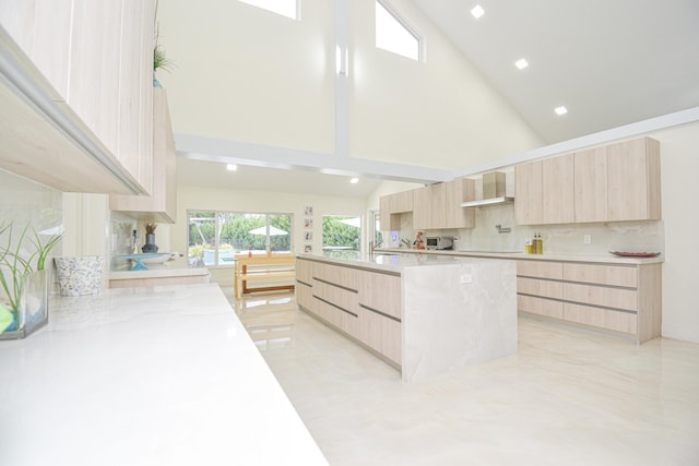 kitchen with modern cabinets, light brown cabinetry, tasteful backsplash, a spacious island, and wall chimney exhaust hood