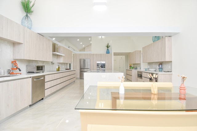 kitchen with appliances with stainless steel finishes, modern cabinets, wall chimney exhaust hood, and light brown cabinets