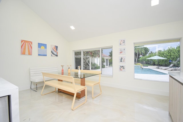 dining room featuring high vaulted ceiling, concrete floors, and baseboards