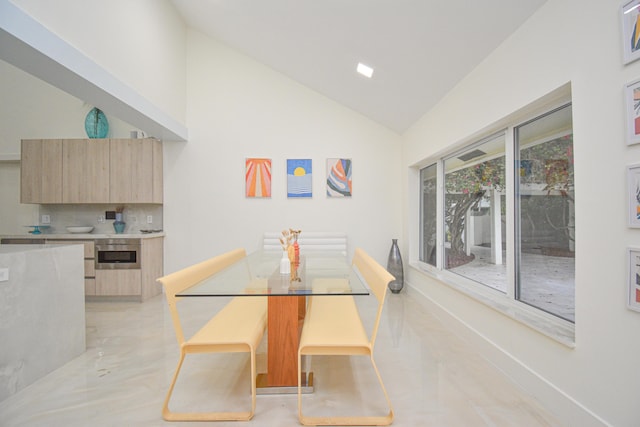 dining space featuring baseboards and high vaulted ceiling