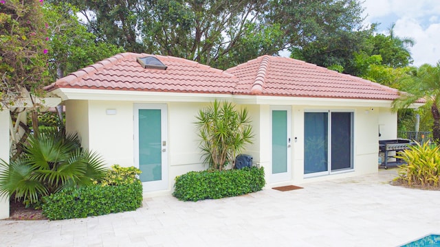 exterior space with a patio area, stucco siding, and a tile roof