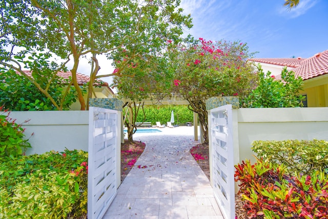 view of gate with a patio area, an outdoor pool, and a fenced backyard