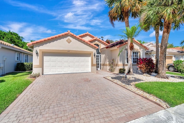 mediterranean / spanish house featuring decorative driveway, an attached garage, a front yard, and stucco siding