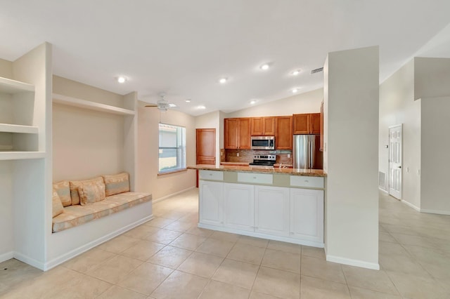 kitchen with light tile patterned floors, decorative backsplash, appliances with stainless steel finishes, a ceiling fan, and vaulted ceiling