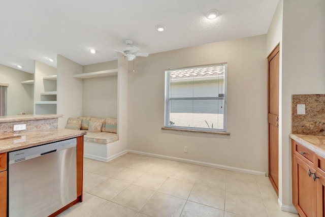 kitchen featuring light tile patterned floors, baseboards, brown cabinetry, dishwasher, and ceiling fan