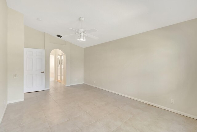 unfurnished room featuring visible vents, arched walkways, baseboards, ceiling fan, and vaulted ceiling