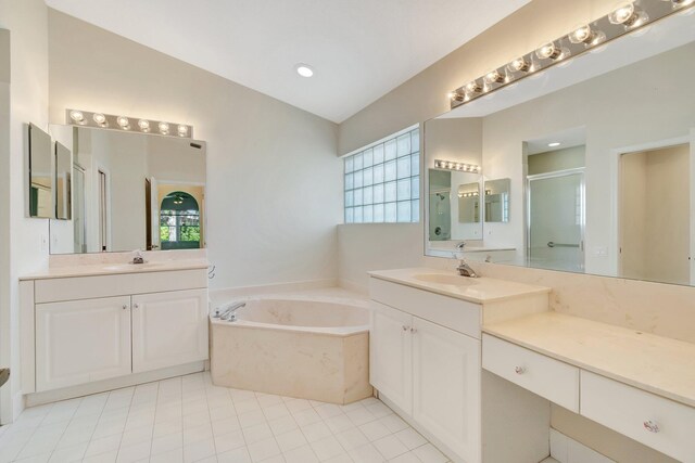 full bath featuring a garden tub, two vanities, a sink, and a shower stall