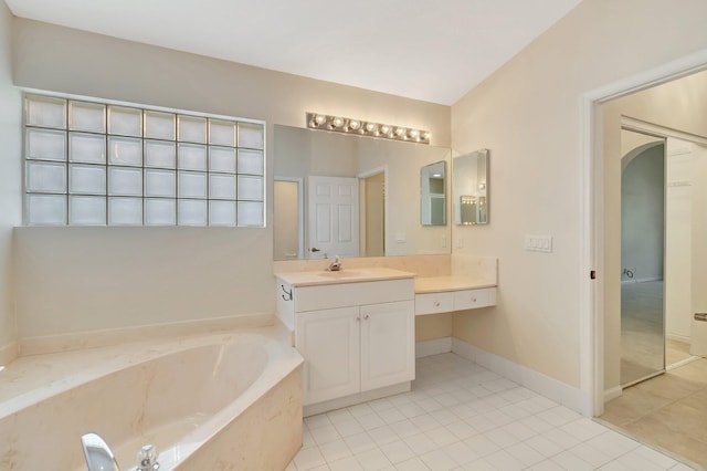 bathroom featuring tile patterned flooring, vanity, a bath, and baseboards