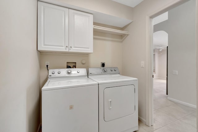 washroom with cabinet space, light tile patterned floors, baseboards, arched walkways, and washing machine and clothes dryer