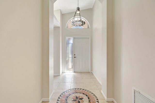 foyer featuring light tile patterned floors, a high ceiling, visible vents, and baseboards