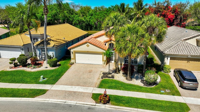 view of front of home with a garage, a tile roof, decorative driveway, stucco siding, and a front lawn