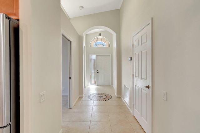 interior space featuring light tile patterned floors, baseboards, visible vents, and arched walkways