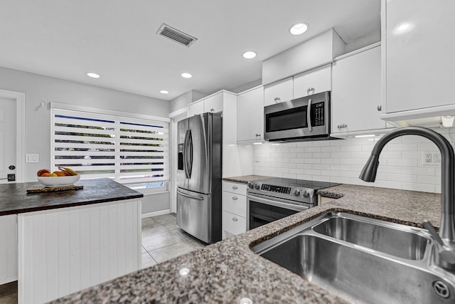 kitchen with visible vents, decorative backsplash, stainless steel appliances, white cabinetry, and a sink
