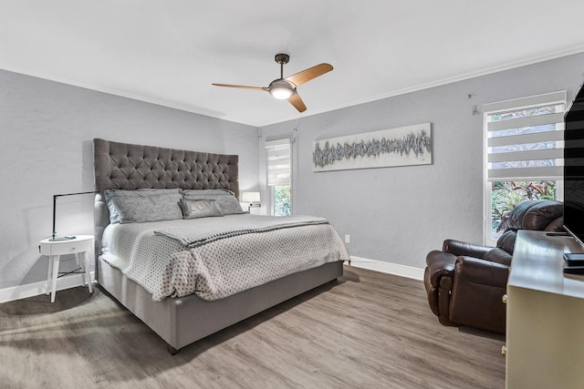 bedroom with ceiling fan, baseboards, wood finished floors, and ornamental molding