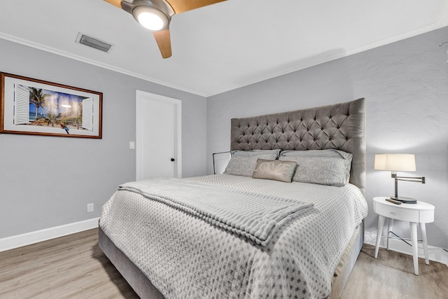 bedroom with visible vents, baseboards, wood finished floors, and crown molding