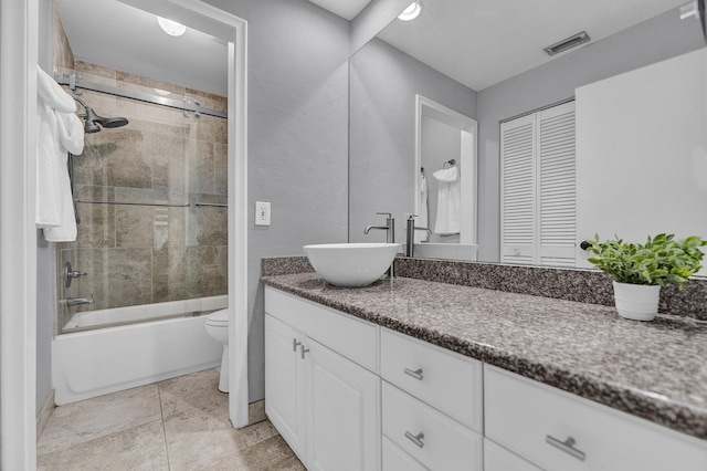 bathroom featuring visible vents, bath / shower combo with glass door, toilet, and vanity