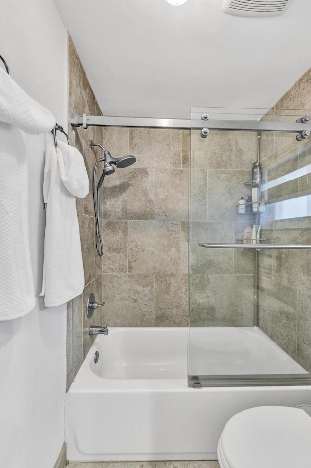 bathroom with toilet, visible vents, and bath / shower combo with glass door