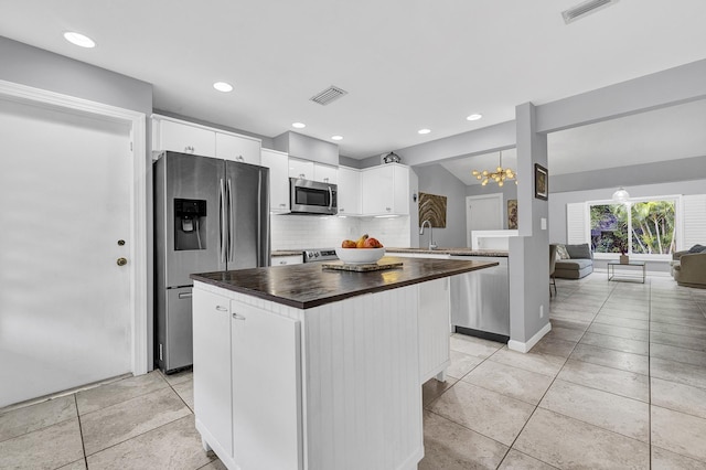 kitchen featuring visible vents, white cabinets, butcher block counters, and stainless steel appliances