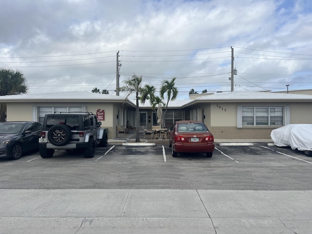 exterior space with uncovered parking, brick siding, and stucco siding