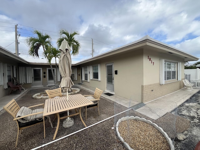 back of property featuring a patio, brick siding, fence, and stucco siding