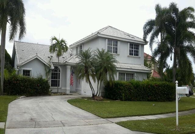 view of front of house featuring driveway, a tile roof, a front lawn, and stucco siding