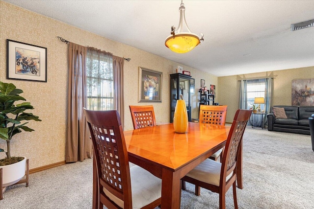 dining area with wallpapered walls, light colored carpet, visible vents, and baseboards