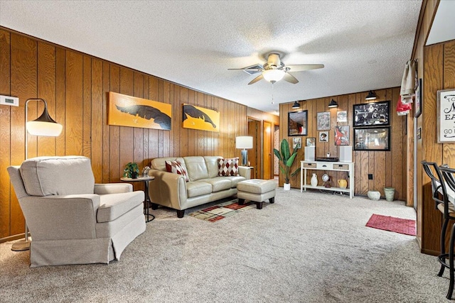 carpeted living room featuring wood walls, a textured ceiling, and ceiling fan