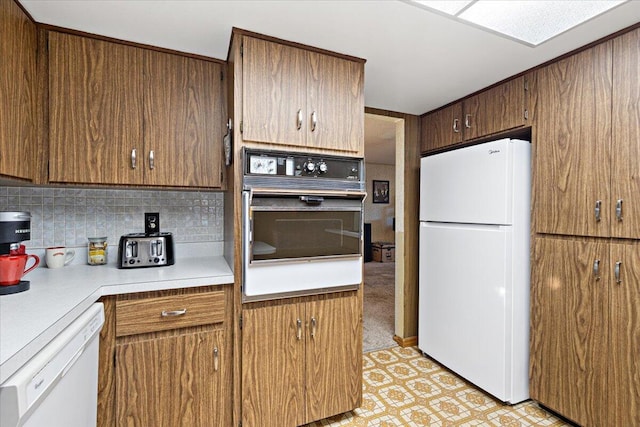 kitchen with decorative backsplash, white appliances, light floors, and light countertops