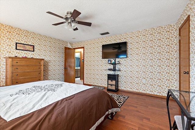 bedroom with visible vents, wallpapered walls, and wood finished floors