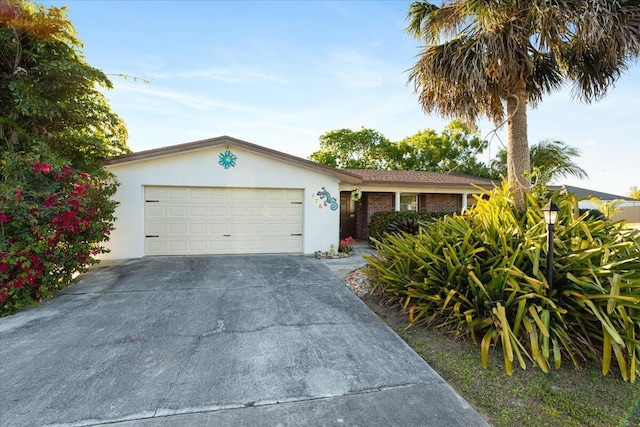 single story home featuring concrete driveway, brick siding, a garage, and stucco siding