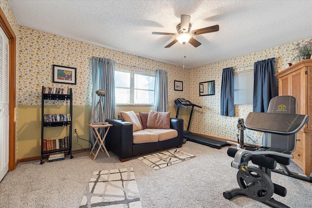 workout area featuring wallpapered walls, baseboards, light carpet, a textured ceiling, and a ceiling fan