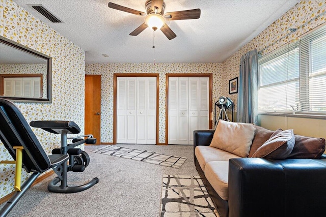 interior space with visible vents, wallpapered walls, ceiling fan, carpet flooring, and a textured ceiling