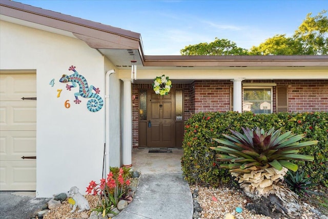 entrance to property with an attached garage and brick siding