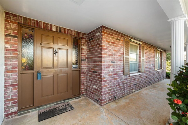 property entrance featuring brick siding and covered porch