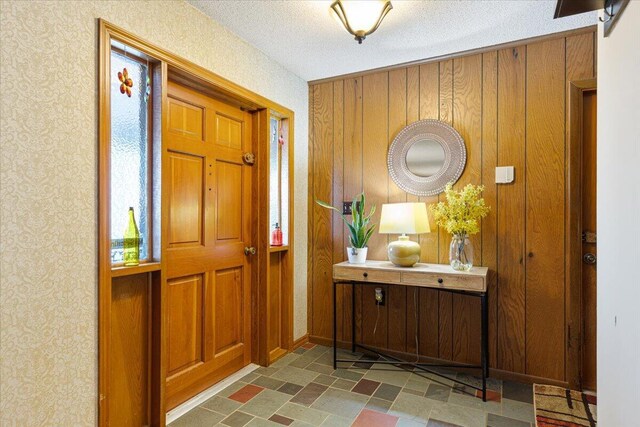 entrance foyer with wooden walls, baseboards, and a textured ceiling